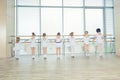 Group of seven little ballerinas standing in row and practicing ballet using stick on the wall Royalty Free Stock Photo
