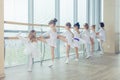 Group of seven little ballerinas standing in row and practicing ballet using stick on the wall Royalty Free Stock Photo