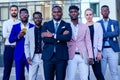 A group of seven successful business people men and woman in stylish suits standing and looking proudly outdoors