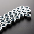 A group of shiny, metallic hexagonal nuts is arranged in a staggered formation on a dark, textured Royalty Free Stock Photo