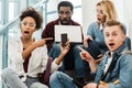 Group of shocked multicultural students with laptop and smartphone Royalty Free Stock Photo