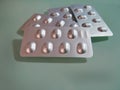 Group of Silver Blister Packs of Pills on Light Green Background