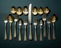 a group of silver and gold flatware on a dark background