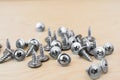 Group of silvery self-tapping screws is arbitrarily positioned on a wooden surface, selective focus, abstract background