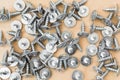 Group of silvery self-tapping screws is arbitrarily positioned on a wooden surface, selective focus, abstract background