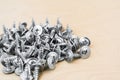 Group of silvery self-tapping screws is arbitrarily positioned on a wooden surface, selective focus, abstract background