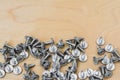 Group of silvery self-tapping screws is arbitrarily positioned on a wooden surface, selective focus, abstract background