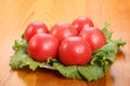 Group of six red ripe tomatoes with water drops lie on a lettuce leaves on a table Royalty Free Stock Photo