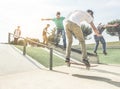Group of skaters friends performing trick and skills in urban contest - Young men training with boards in skate park at sunset -