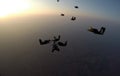 A group of skydivers perform a jump at sunset.