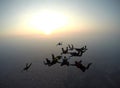 A group of skydivers perform a jump at sunset.