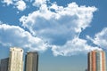 Group of skyscrapers or flat block buildings on thick clouds and blue sky background. Closeup view of modern urban architecture Royalty Free Stock Photo