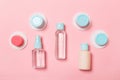 Group of small bottles for travelling on pink background. Copy space for your ideas. Flat lay composition of cosmetic products.