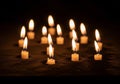 A group of small, lit candles arranged in a scattered pattern on a Royalty Free Stock Photo
