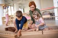 Group of small nursery school children with teacher sitting on floor indoors in classroom, montessori learning.