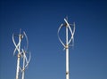 Group of small vertical wind turbines against a blue sky