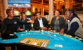 Group of smartly dressed diverse individuals gathered around a casino table