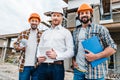 group of smiling architects in hard hats looking at camera in front of Royalty Free Stock Photo