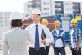 Group of smiling builders in hardhats outdoors