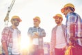 Group of smiling builders in hardhats outdoors