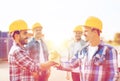 Group of smiling builders shaking hands outdoors