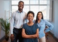 Group of smiling business people pose arms folded in office, diverse trio