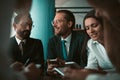 Group of smiling businesspeople using phones while communicating in meeting or negotiation. Business partnership concept
