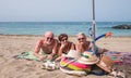 Group of smiling caucasian seniors lying on the sea beach sunbathing enjoying leisure time - happy mature women and man looking at Royalty Free Stock Photo