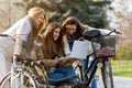 Group of smiling college girls on park bench working on laptop Royalty Free Stock Photo