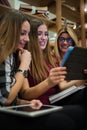 Group of smiling female students looking at tablet in library Royalty Free Stock Photo