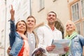 Group of smiling friends with city guide and map Royalty Free Stock Photo