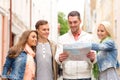 Group of smiling friends with map exploring city Royalty Free Stock Photo