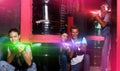 Smiling friends playing laser tag game with laser guns in lab