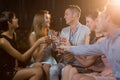 Group of smiling friends sitting on sofa and toasting a glasses of champagne Royalty Free Stock Photo