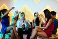 Group of smiling friends sitting on sofa and toasting a glasses of champagne Royalty Free Stock Photo