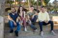 A group of smiling friends sitting on the steps of a park.