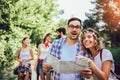 Smiling friends walking with backpacks in woods - adventure, travel, tourism, hike and people concept Royalty Free Stock Photo