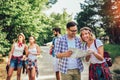 Smiling friends walking with backpacks in woods - adventure, travel, tourism, hike and people concept Royalty Free Stock Photo