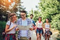 Smiling friends walking with backpacks in woods - adventure, travel, tourism, hike and people concept Royalty Free Stock Photo