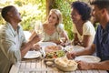 Group Of Smiling Multi-Cultural Friends Outdoors At Home Eating Meal And Drinking Wine Together Royalty Free Stock Photo