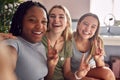 Group Of Smiling Multi-Cultural Teenage Girl Friends Posing For Selfie On Mobile Phone At Home Royalty Free Stock Photo