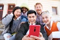 Group of Smiling people using mobile phone outdoors. Cheerful guys and girls friends having fun watching Royalty Free Stock Photo