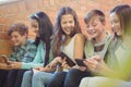 Group of smiling school friends sitting on staircase using mobile phone Royalty Free Stock Photo