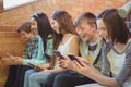 Group of smiling school friends sitting on staircase using mobile phone Royalty Free Stock Photo