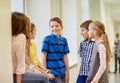 Group of smiling school kids talking in corridor