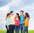 Group of smiling teenagers over blue sky and grass Royalty Free Stock Photo