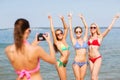 Group of smiling women photographing on beach