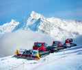 Group of snow groomers over Alps mountain summits