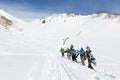 Group snowboarders climbing the steep mountain for freeride