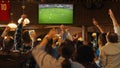 Group of Soccer Fans Watching a Live Football Match in a Sports Bar. People Standing in Front of a Royalty Free Stock Photo